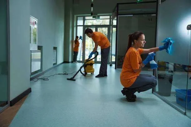 Equipe de limpeza profissional higienizando corredor de escritório com aspirador e produtos